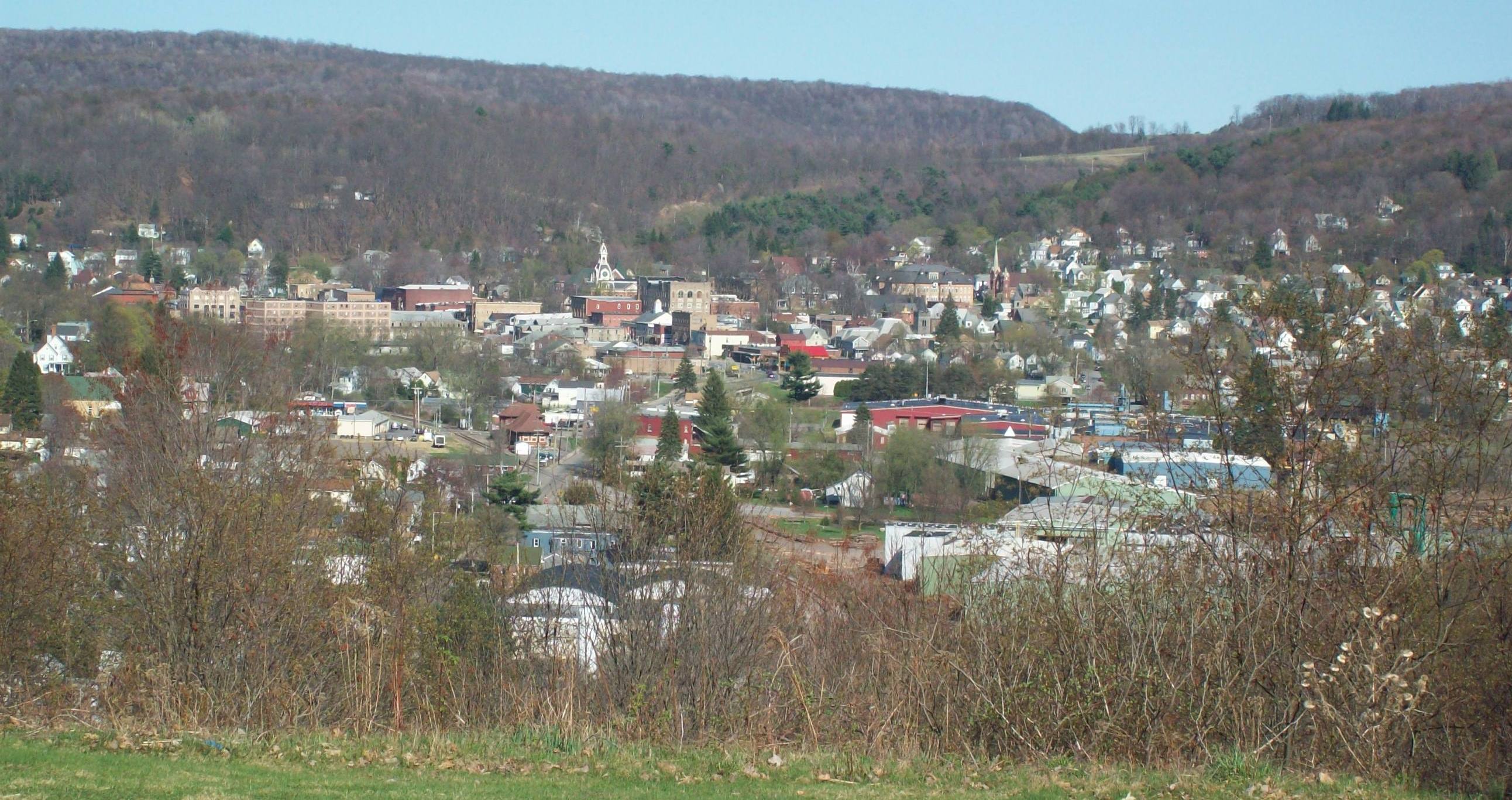 Wide view of Ridgway, Pennsylvania nestled in a forested river valley, seen from an overlook.
